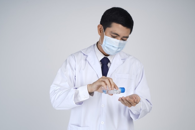 Asian doctor man wearing white coat, medical mask and holdinging sanitizer