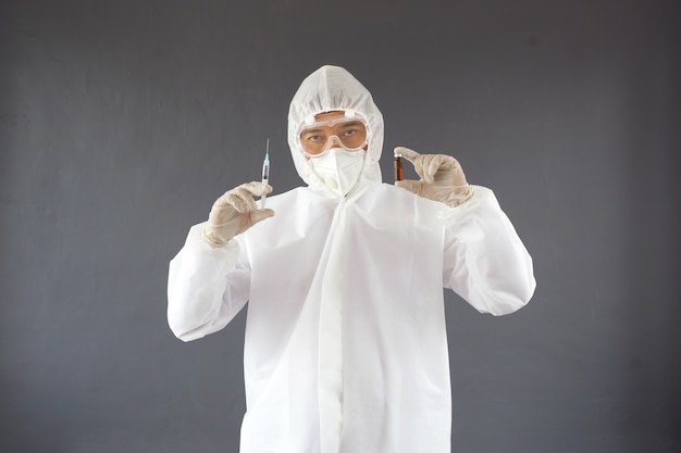 Asian Doctor in ppe suit posing with holding syringe and vial of medicine