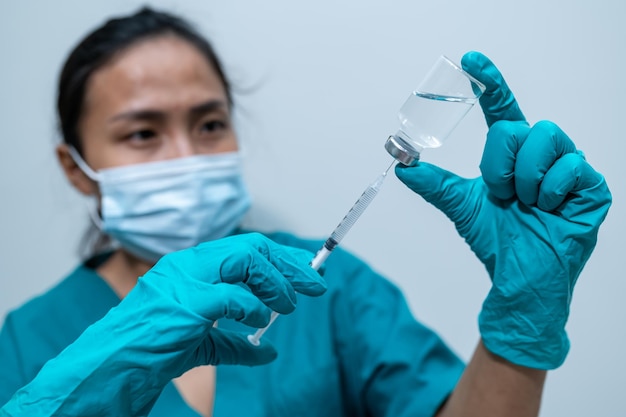 Asian doctor with Syringe and vaccine for protect covid19 virus on white background