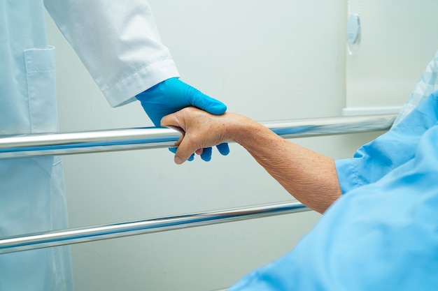 Asian elder senior woman patient holding bed rail while lie down with hope waiting her family in hospital