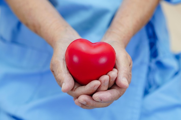 Asian elder senior woman patient holding red heart in hospital