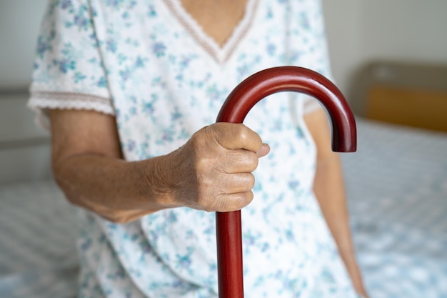 Asian elderly disability woman holding waling stick wood cane round handle walking aid for help to walk