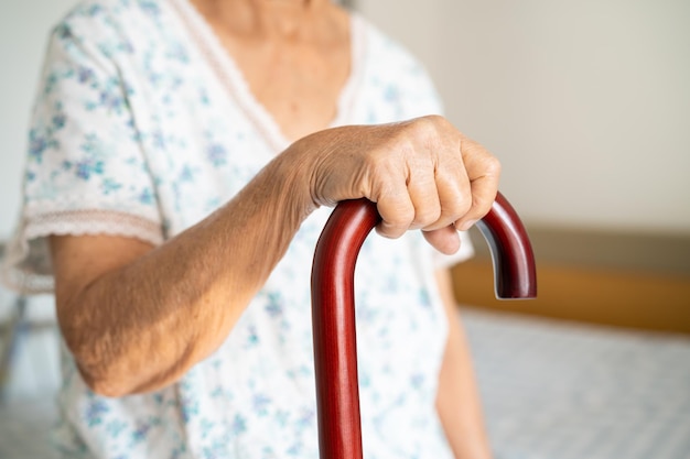 Asian elderly disability woman holding waling stick wood cane round handle walking aid for help to walk