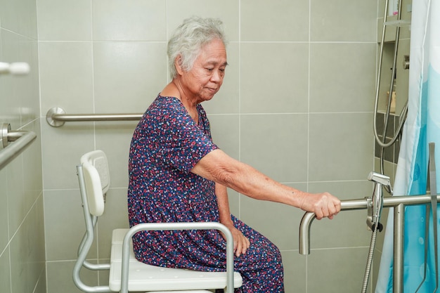 Asian elderly old woman patient use toilet support rail in bathroom handrail safety grab bar security in nursing hospital