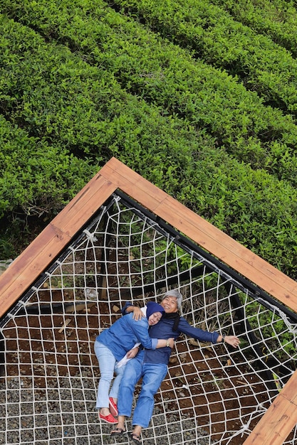 Asian elderly romantic couple lying on relaxing net at tea plantation Happy and healthy couple