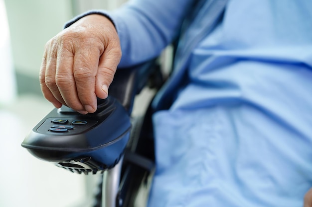 Asian elderly woman disability patient sitting on electric wheelchair in park medical concept