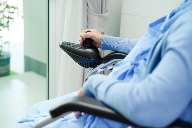 Asian elderly woman disability patient sitting on electric wheelchair in park medical concept