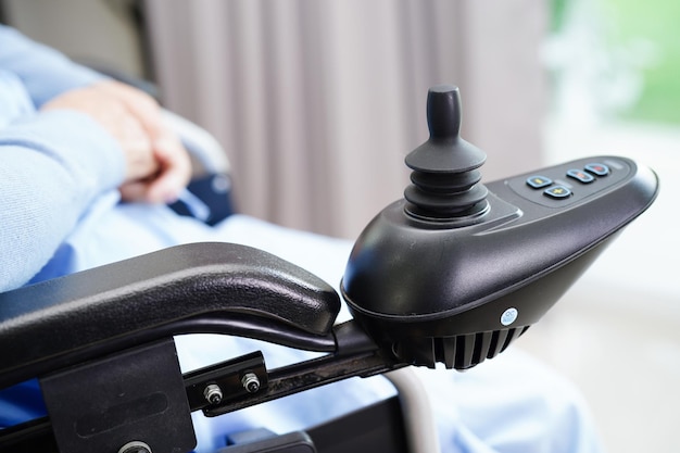 Asian elderly woman disability patient sitting on electric wheelchair in park medical concept