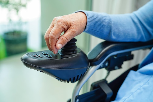 Asian elderly woman disability patient sitting on electric wheelchair in park medical concept