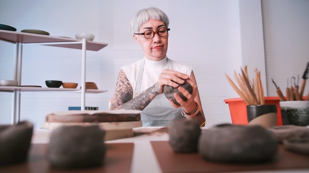 Asian elderly woman enjoying pottery work at home A female ceramicist is making new pottery in a studio