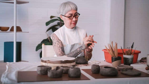 Asian elderly woman enjoying pottery work at home A female ceramicist is making new pottery in a studio