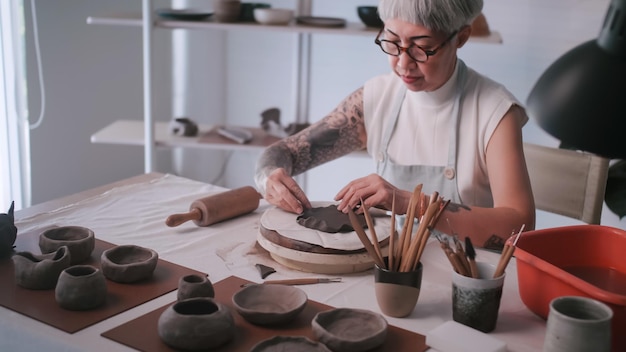 Asian elderly woman enjoying pottery work at home A female ceramicist is making new pottery in a studio