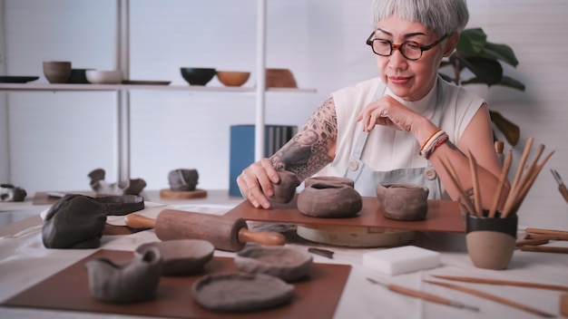 Asian elderly woman enjoying pottery work at home A female ceramicist is making new pottery in a studio