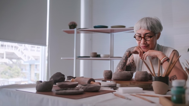 Asian elderly woman enjoying pottery work at home A female ceramicist is making new pottery in a studio