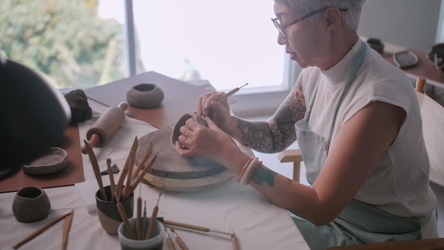 Asian elderly woman enjoying pottery work at home A female ceramicist is making new pottery in a studio