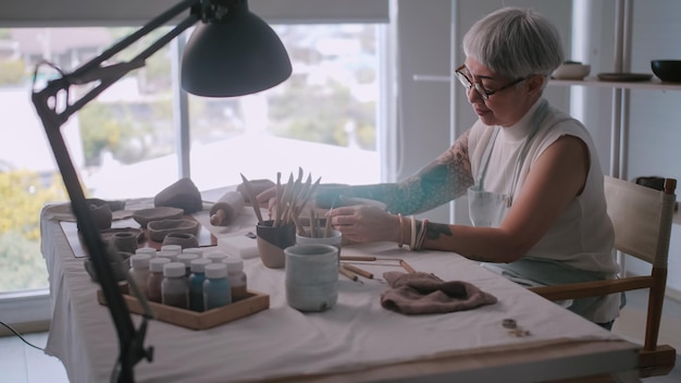 Asian elderly woman enjoying pottery work at home A female ceramicist is making new pottery in a studio