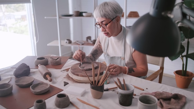 Asian elderly woman enjoying pottery work at home A female ceramicist is making new pottery in a studio