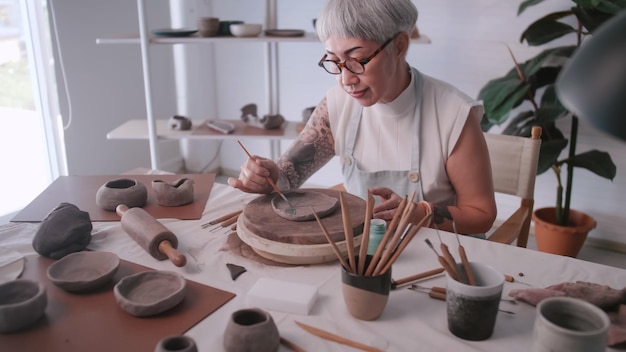 Asian elderly woman enjoying pottery work at home A female ceramicist is making new pottery in a studio