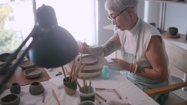 Asian elderly woman enjoying pottery work at home A female ceramicist is making new pottery in a studio