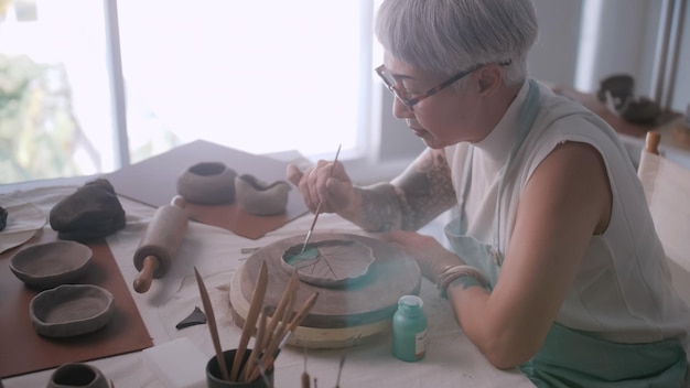 Asian elderly woman enjoying pottery work at home A female ceramicist is making new pottery in a studio