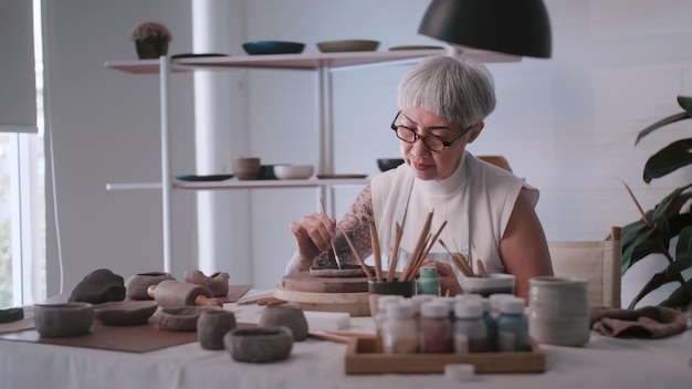 Asian elderly woman enjoying pottery work at home A female ceramicist is making new pottery in a studio