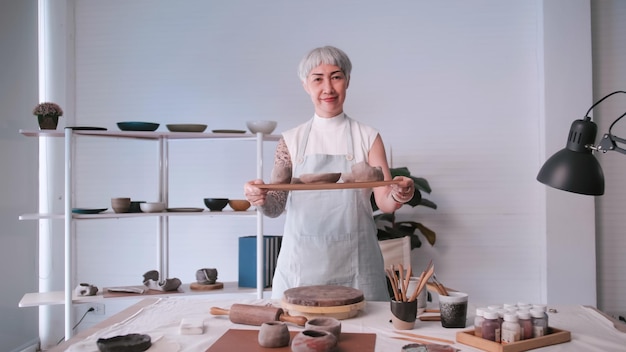 Asian elderly woman enjoying pottery work at home A female ceramicist is making new pottery in a studio