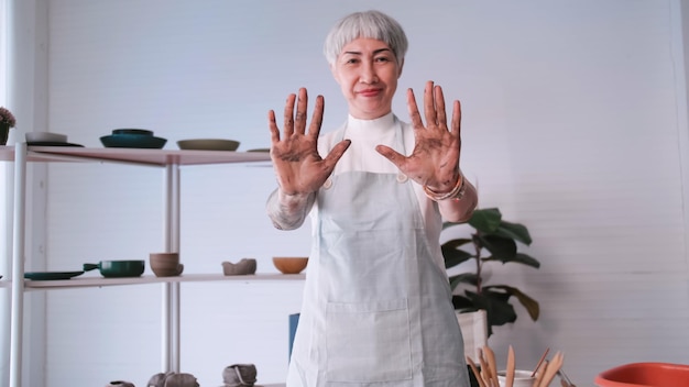 Asian elderly woman enjoying pottery work at home A female ceramicist is making new pottery in a studio