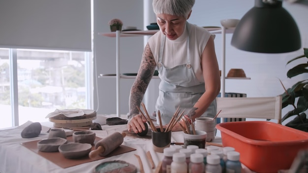 Asian elderly woman enjoying pottery work at home A female ceramicist is making new pottery in a studio