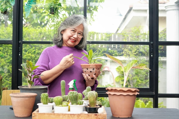 Asian elderly woman at home She smiles happily to be able to plant trees and take care of them soothing the mind and good health The concept of living for the elderly in retirement