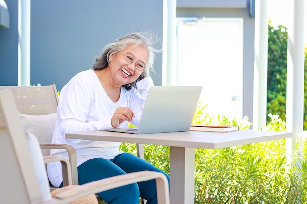 Asian elderly woman online video call on laptop computer Talk to friends or grandchildren She smiled happily concept of social distancing Prevent coronavirus infection