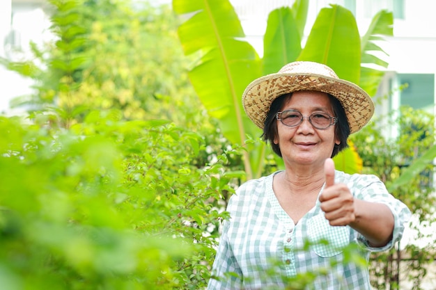 Asian elderly woman smiling happily She lives at home has planted trees takes care of her garden The concept of living in retirement to be happy health care