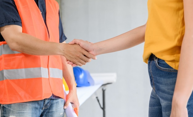 Asian Engineer and architect handshake at construction property site. Teamwork and Successful housing estate building project