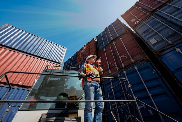 Asian engineer man Standing on a container forkift  using a communication radio WalkieTalkie