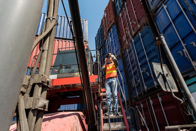 Asian engineer man using binoculars and radio communication working at the warehouse container