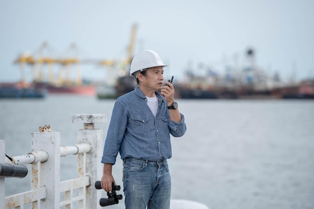 Asian engineer man using walkie talkie and binoculars Compare with real locations For construction