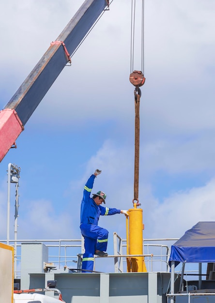 Asian engineer with crane truck transferring hydraulic cylinder into sand suction dredger ship