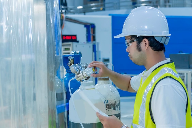 Asian engineer working at Operating hallThailand people wear helmet workHe worked with diligence and patienceHe checked the valve regulator at the hydrogen tank