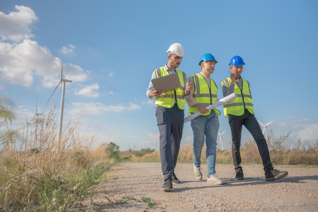 Asian engineers working in fieldwork outdoor Workers walking and inspect construction and machine around project site Wind turbine electrical of clean resource enerdy and environment sustainable