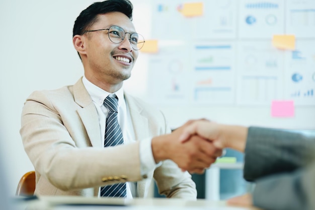 Asian entrepreneurs handshakes to congratulate the agreement between the two companies to enhance investment and financial strength deal concept