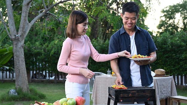 Asian family having a barbecue party at home. Cooking grilled bbq for dinner in backyard. Lifestyle on summer holiday.