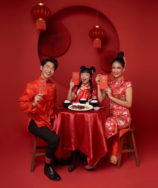 Asian family holding angpao or red packet monetary gift and dinner food for chinese new year