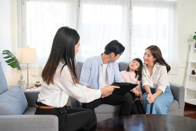 Asian family meeting with female real estate agent or insurance consultant offering promotions