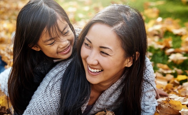 Photo asian family mom and child in autumn park for bonding support and love for behavior development parent girl and happy with hug to relax for childhood memories trust and care at home together