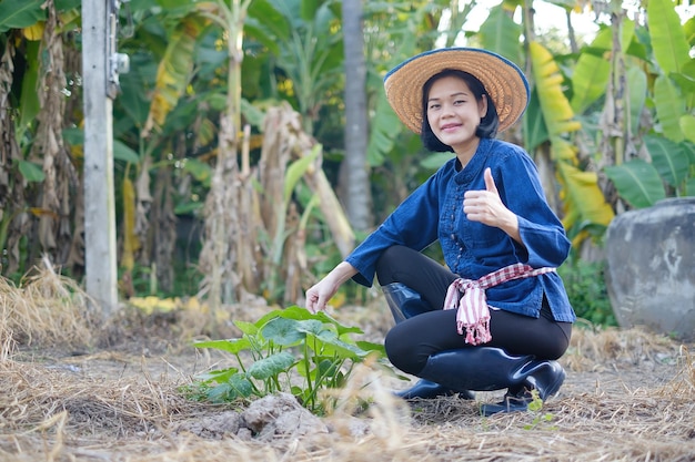 Asian farmer woman sitting and thumb up with plant