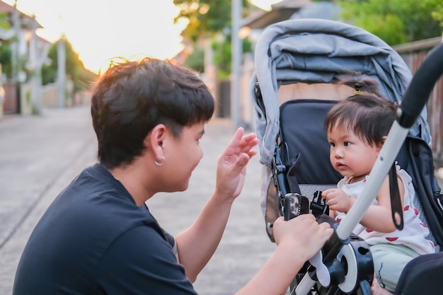 Asian father and daughter or son cute girl making kiss feeling happy and enjoy on baby stroller