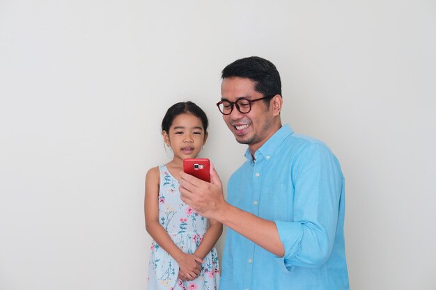 Asian father smiling happy while showing  mobile phone screen to his daughter