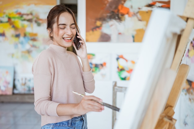 Asian female artist painting on canvas doing some art projects on her studio workshop