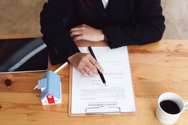 Asian female bank employee asking a customer to read the contract before signing to agree to buy a house real estate concepts