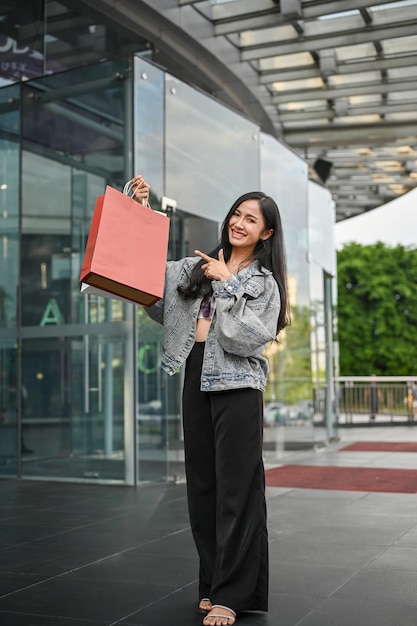 Asian female carrying her shopping bag standing in front of the shopping mall's entrance