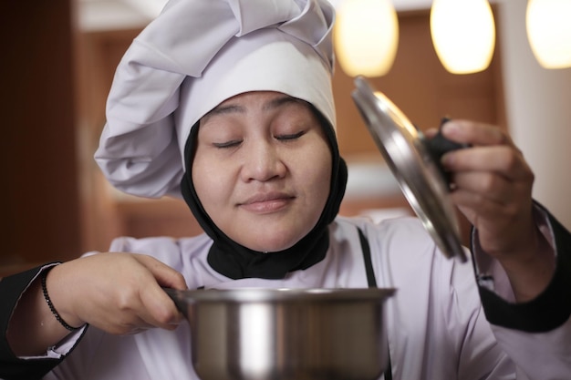 Asian female chef smelling food aroma that she cooked